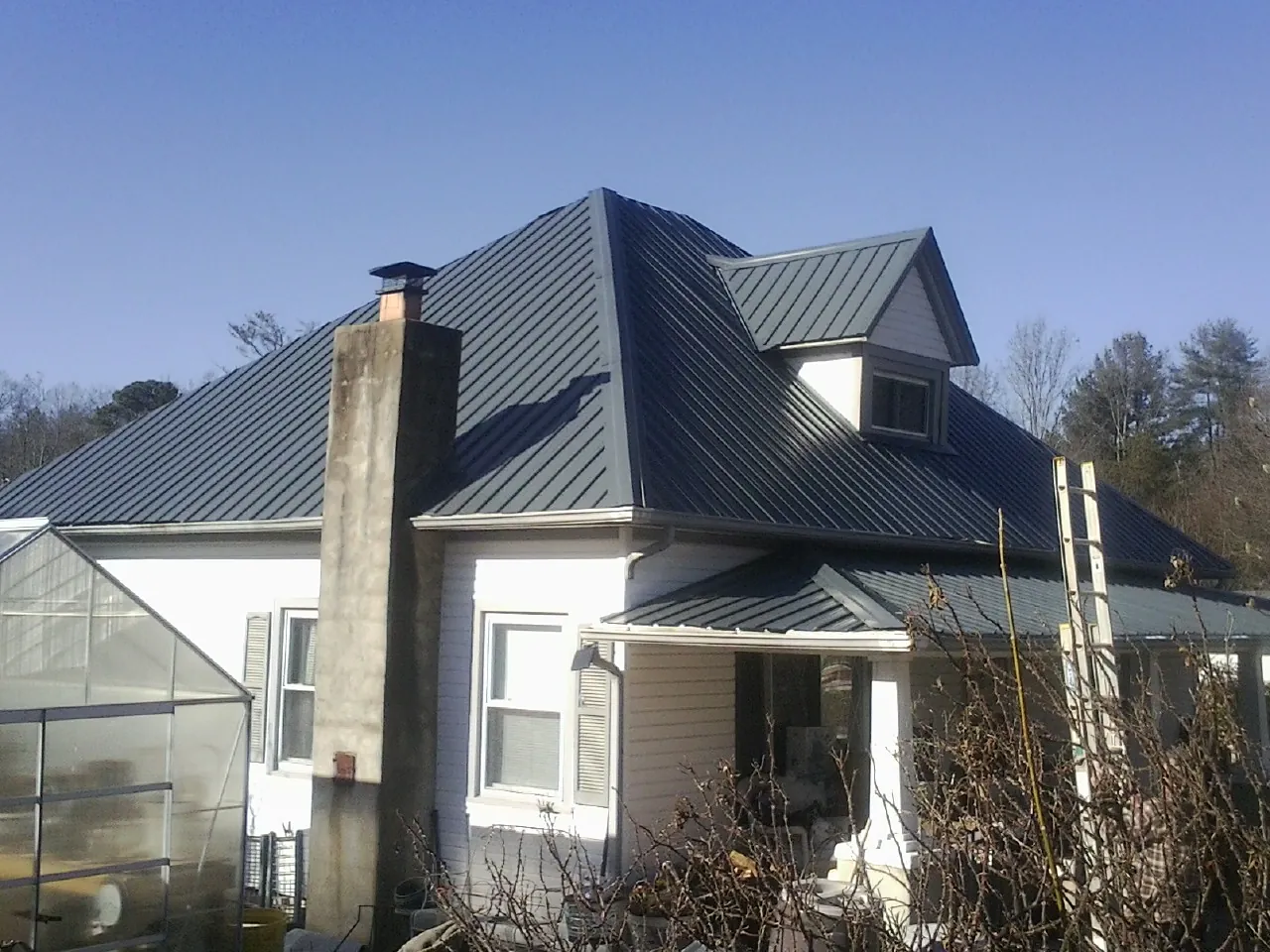 Dark blue standing seam metal roof on a white farmhouse with dormer — Slate & Tile Roof Repair by Roofing Brothers in Cantrall