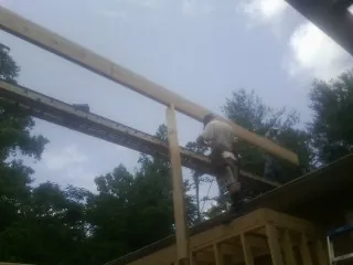 Carpenter setting a ridge beam over a new addition frame — Ice Dam Removal by Roofing Brothers in Cantrall