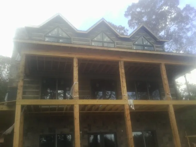 Dormers and porch framing on a large log home under construction — Roof Coating work by our crew in Cantrall