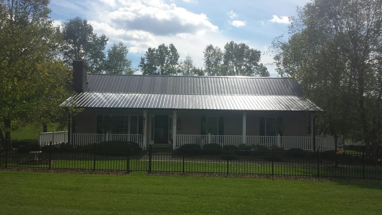 Gray metal roof on a brick ranch with a full width front porch — Gutter Guard Installation work by our crew in Cantrall