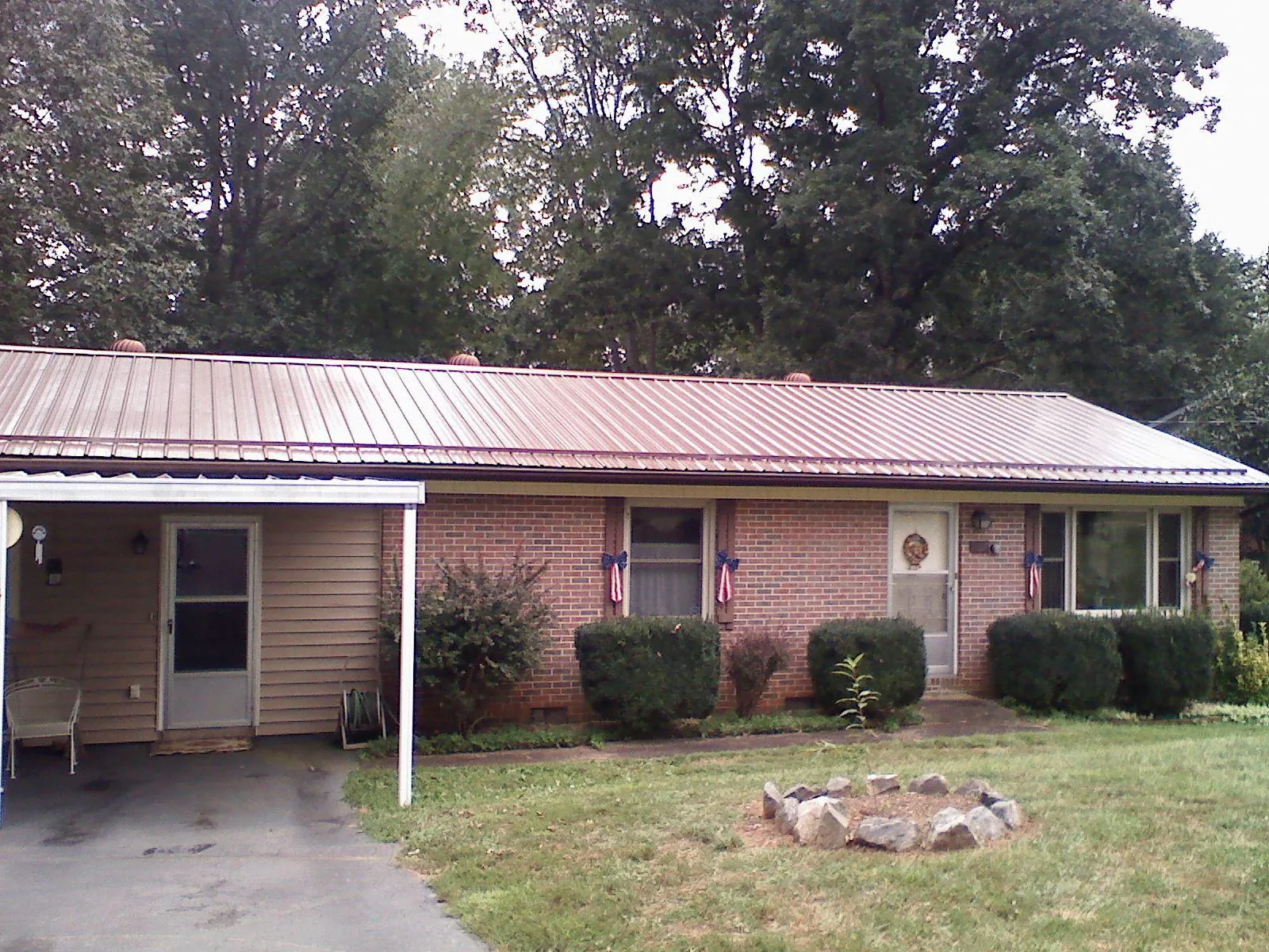 Bronze metal roof and carport on a brick ranch home — Roof Repair work by our crew in Cantrall